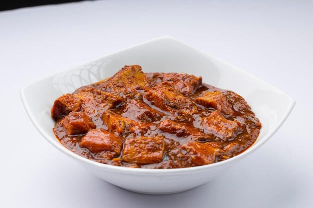 Receita caseira de masala de carne ou curry disposta em tigela branca com fundo branco