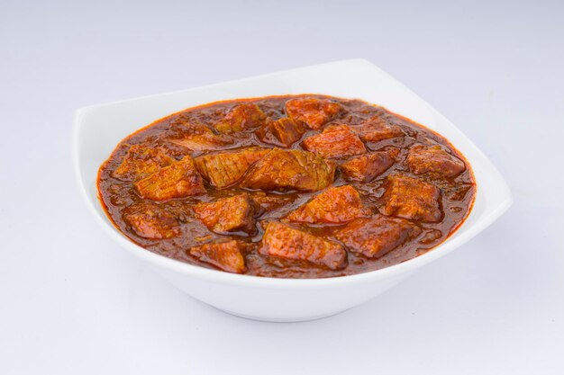 Receita caseira de masala de carne ou curry disposta em tigela branca com fundo branco