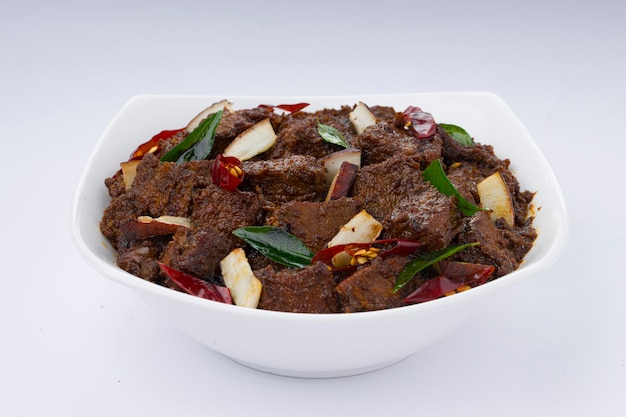 Receita caseira de masala ou curry de carne assada disposta em tigela branca com fundo branco