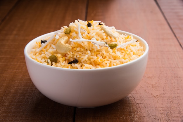 Receita de arroz doce de coco, também conhecida como narali bhat, feita com açafrão, caju, cravo e servida em uma tigela branca. Comida popular konkani ou maharashtriana.