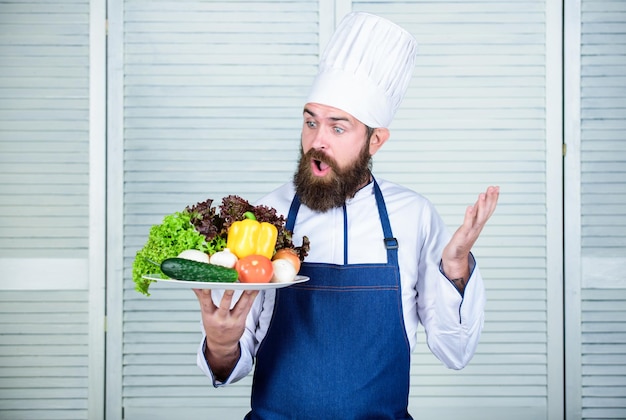 Receita de chef de homem barbudo surpreso Cozinha culinária Vitamina Salada vegetariana com legumes frescos Dieta de alimentos orgânicos Cozinha de alimentos saudáveis Hipster maduro com barba Peça conselhos