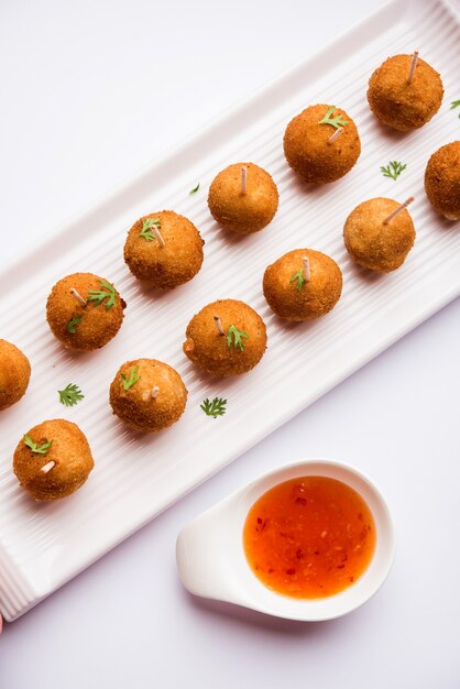 Receita de pirulito crocante de vegetais feita com batata cozida com temperos cobertos com farinha de milho e cobertura de migalhas de pão e depois frita, servida com palito de dente ou sorvete