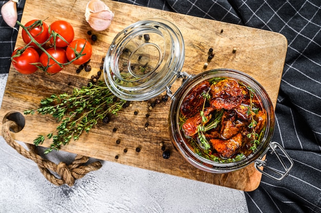 Receita para cozinhar tomates secos em azeite com especiarias e ervas. Superfície cinza. Vista do topo