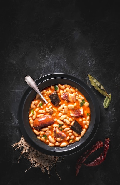 Receita tradicional de feijão com chouriço e chouriço chamada Fabada Asturiana em mesa escura