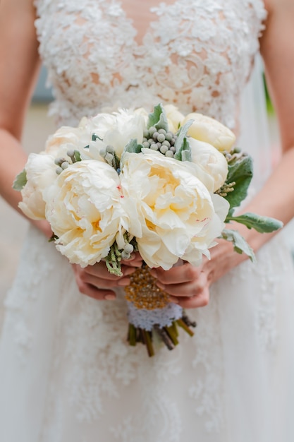 Recém casado casal. Dia do casamento. Buquê da noiva nas mãos, o abraço do noivo.