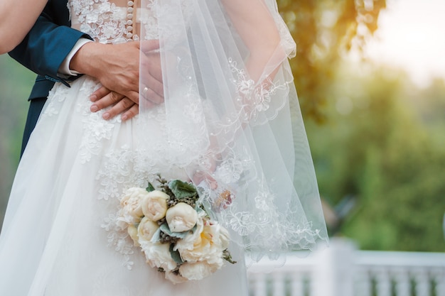 Recém casado casal. Dia do casamento. Buquê da noiva nas mãos, o abraço do noivo.