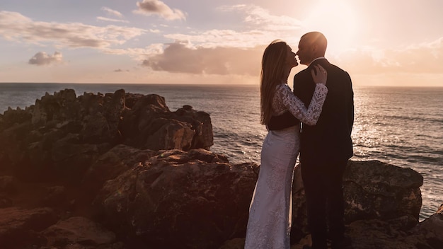 Recém-casados abraçando e beijando na costa rochosa do oceano ov