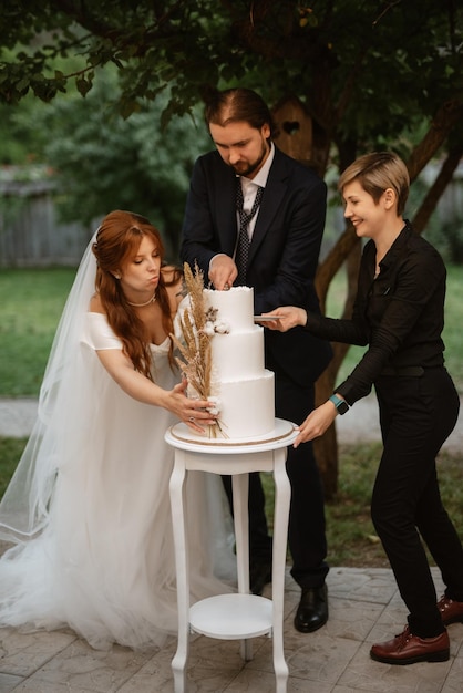 Foto recém-casados cortam alegremente e provam o bolo de casamento