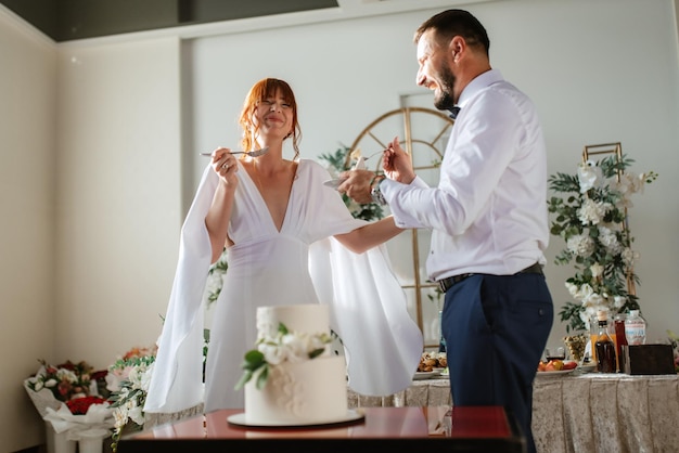 Foto recém-casados cortam alegremente e provam o bolo de casamento