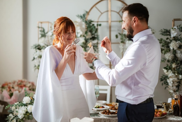 Recém-casados cortam alegremente e provam o bolo de casamento