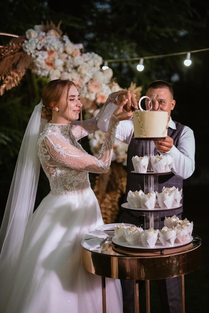 Recém-casados cortam alegremente e provam o bolo de casamento