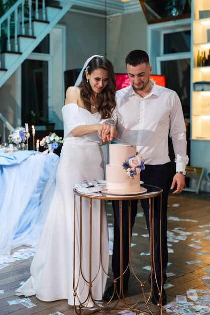 Foto recém-casados cortam alegremente, riem e provam o bolo de casamento