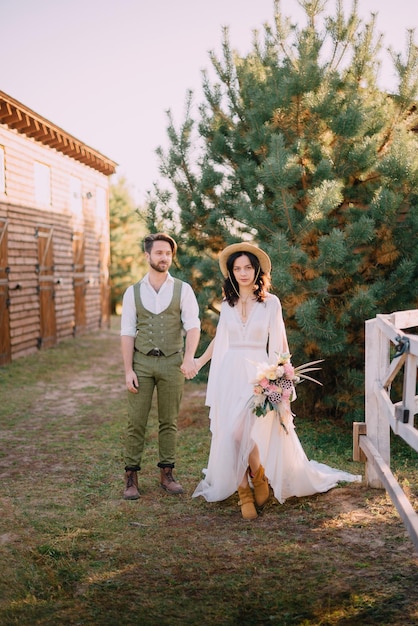 Foto recém-casados de estilo boho caminham na natureza, dia de verão