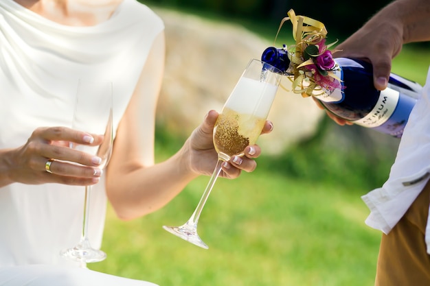 Foto recém-casados derramam vinho em copos.