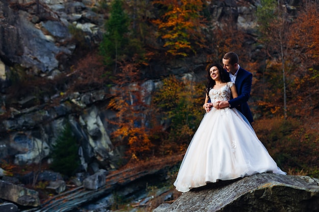 Recém-casados em uma pedra grande, sem fundo de pedras e autum