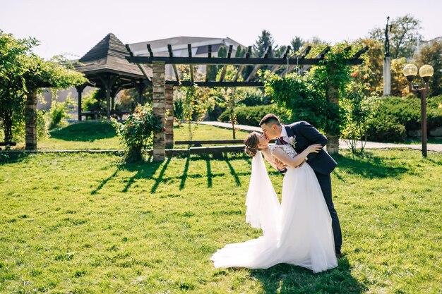 Recém-casados estão de pé e se beijando no jardim botânico verde cheio de vegetação Cerimônia de casamento