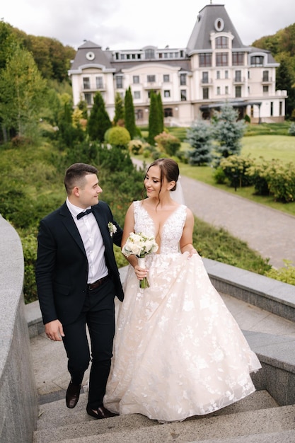 Recém-casados felizes andando no grande parque juntos noivo bonito uma noiva elegante em seu casamento