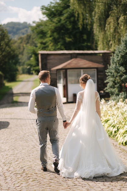 Recém-casados felizes caminhando ao ar livre no dia do seu casamento. Noivo e noiva passam um tempo juntos