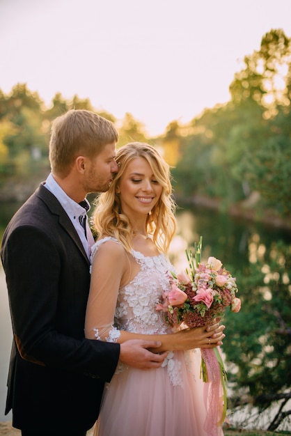 Recém-casados felizes em pé ao pôr do sol