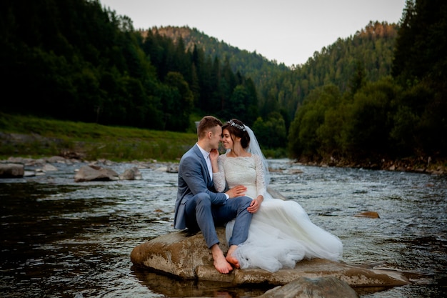 Recém-casados felizes, sentado em uma pedra