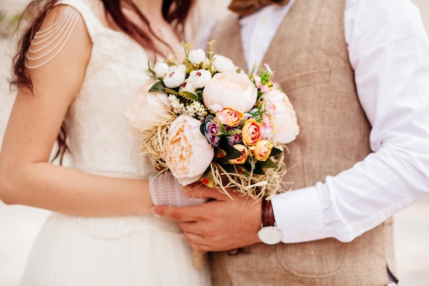 Recém-casados segurando o buquê de casamento juntos