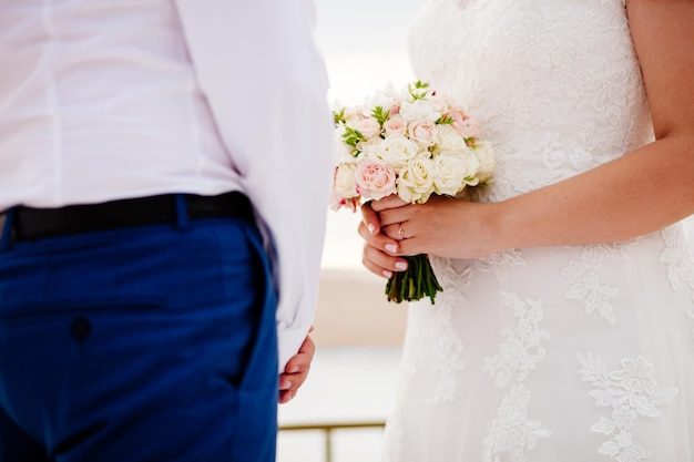 Recém-casados segurando o buquê de casamento juntos