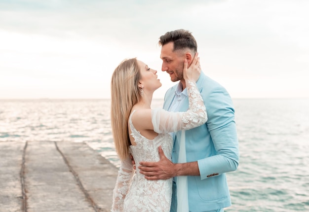 Recém-casados sensuais ficam de mãos dadas no fundo do mar azul caminhada de casamento em uma praia de areia no fundo do céu azul