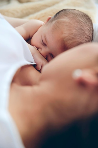 Recém-nascido deitado na cama com a mãe