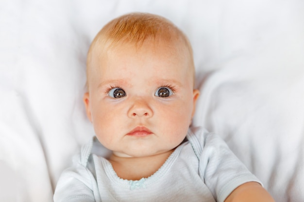 Recém-nascido menina bonitinha com cara engraçada, olhando para a câmera no fundo branco infantil bebê descansando p ...