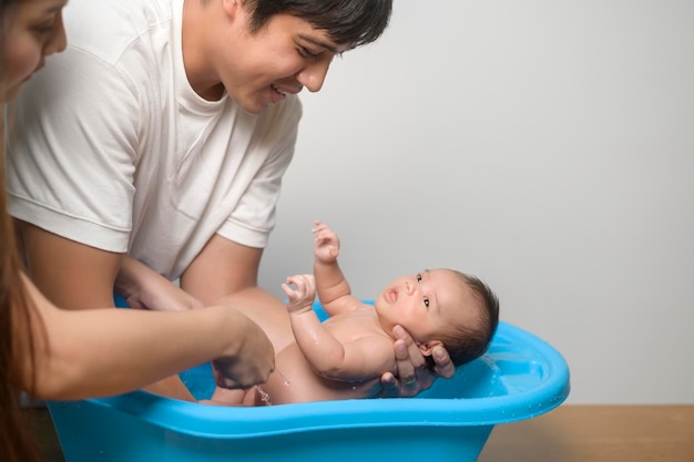 Recém-nascido tomando banho por feliz mãe e pai família e conceito de amor