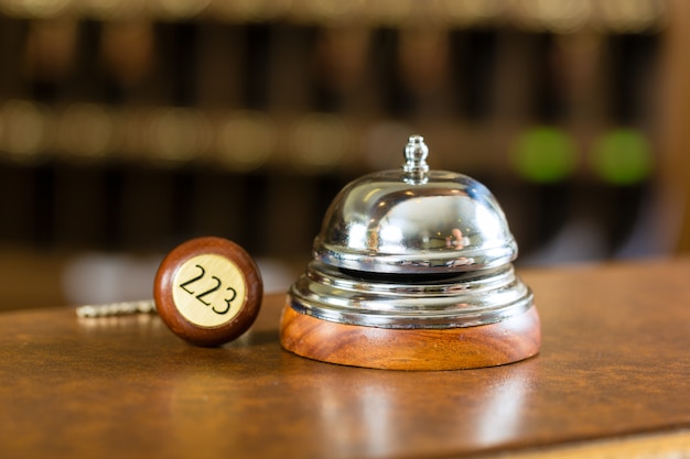 Recepção, sino de hotel e chave deitada na mesa