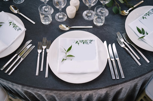 Recepción de mesa de cena de boda platos redondos blancos sobre una mesa redonda con mantel gris blanco