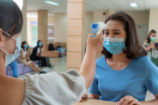 Recepcionista e convidado usando máscara facial na recepção enquanto conversam no escritório ou hospital