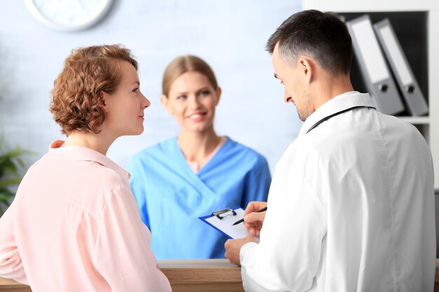 Recepcionista e médico com cliente no hospital