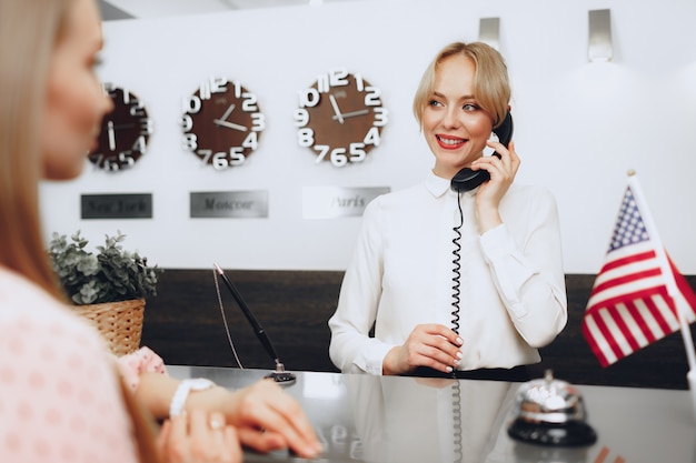 Recepcionista femenina en el hotel hablando por teléfono en el trabajo