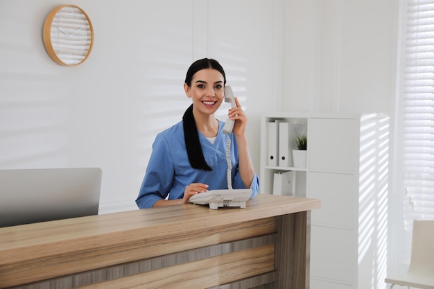 Recepcionista hablando por teléfono en la encimera del hospital