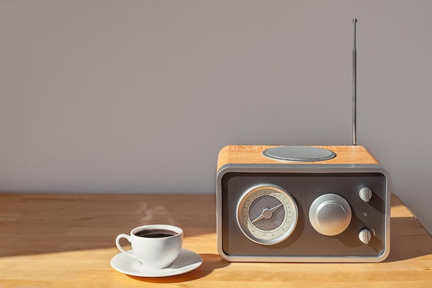 Un receptor de radio y una taza de café en una mesita de noche de madera al sol de la mañana