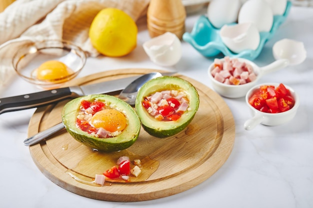 Receta de almuerzo cetogénico de aguacate con huevo, jamón, tomates y queso antes de hornear