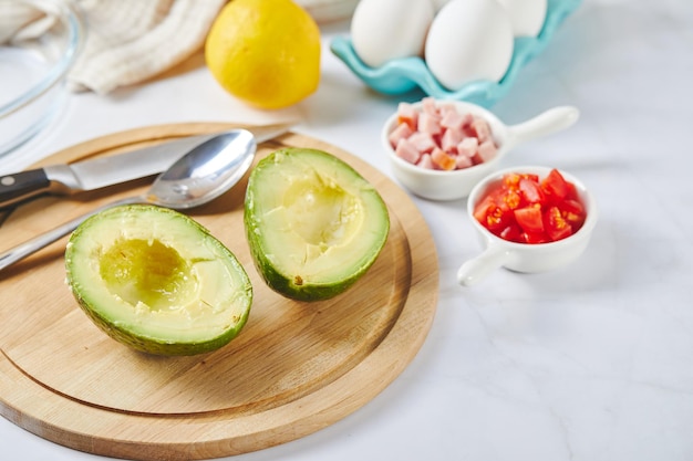 Receta de almuerzo cetogénico de aguacate con huevo, jamón, tomates y queso antes de hornear