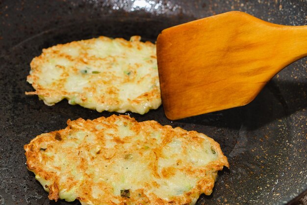 Receta para fritters de calabacín Paso 5 - freír panqueques en la sartén hasta que sean de color marrón dorado Volver panqueques con espátula de madera