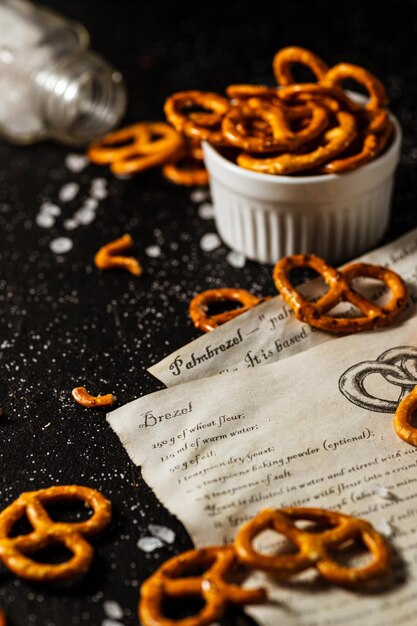 La receta para hacer pretzels está escrita en una hoja de papel, junto a ella se encuentran la sal y los pretzels.