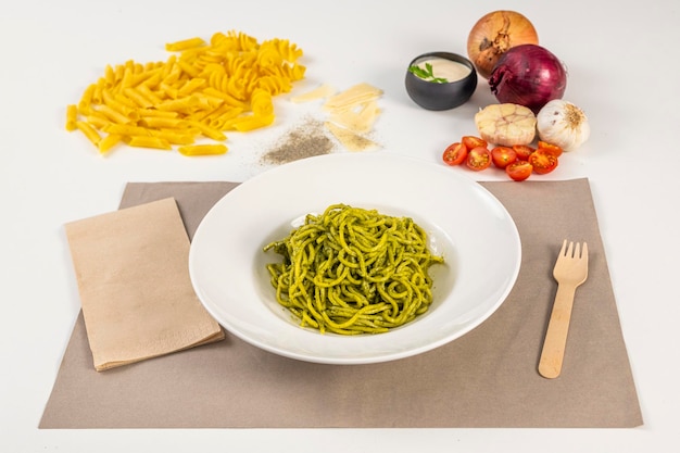 Receta italiana de espaguetis al pesto con tomates, cebollas, ajo y pasta fresca sobre mantel de papel