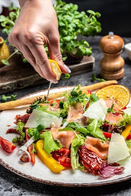 Foto receta de mariscos frescos. salmón ahumado, lechuga, tomates secos y salsa de queso. congelar movimiento salpicaduras gotas de jugo de limón, comida sana,