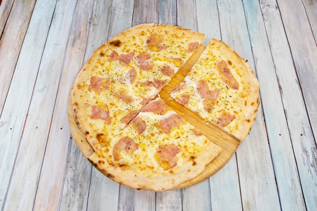 Foto receta de pizza italiana carbonara mediana con guanciale y queso con cebolla blanca guisada sobre mesa de madera