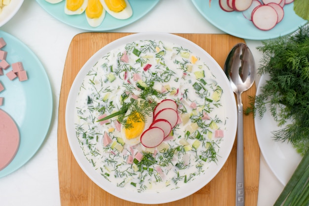 Receta de sopa okroshka fría nacional rusa en un plato blanco sobre una luz