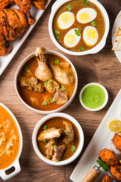 Receta variada de comida india no vegetariana servida en grupo. Incluye Chicken Curry, Mutton Masala, Anda o egg curry, Butter chicken, biryani, tandoori murg, chicken-tikka y naa, roti para ramadán