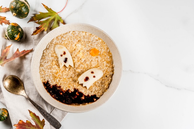 Recetas de comida de Halloween para niños, desayuno para niños con avena dulce de calabaza con fantasmas de plátano comestibles y salsa de chocolate