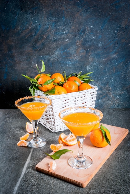 Recetas e ideas de cócteles de frutas de invierno, mandarina martini margarita con mandarinas frescas en la cesta, sobre fondo oscuro, espacio de copia