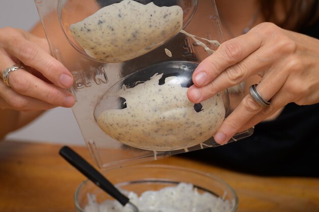 Recheio de moldes com chocolate branco derretido e pedaços de biscoito para preparar ovos de páscoa