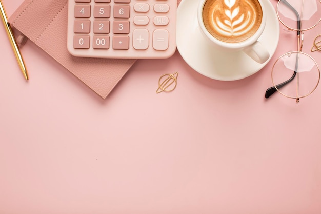 Rechner eine Tasse Kaffee mit einem schönen Muster und einem Notizblock auf einem rosa Hintergrund Platz für Text